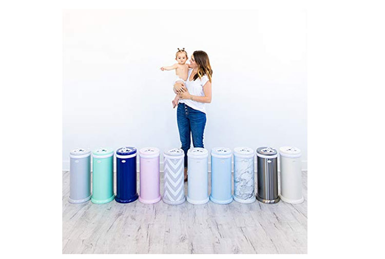 Woman is carrying her baby while in front of them is a diaper pail