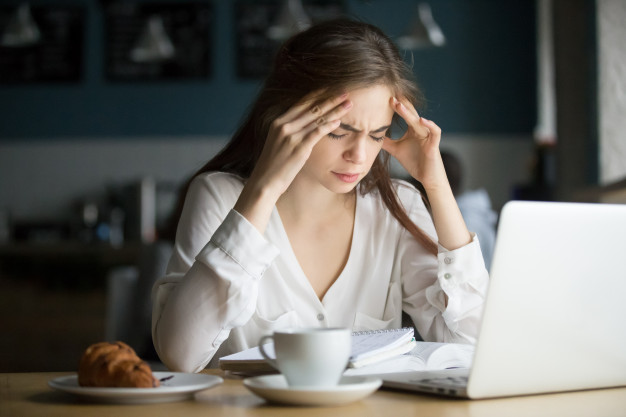 woman working on laptop suffering with headache